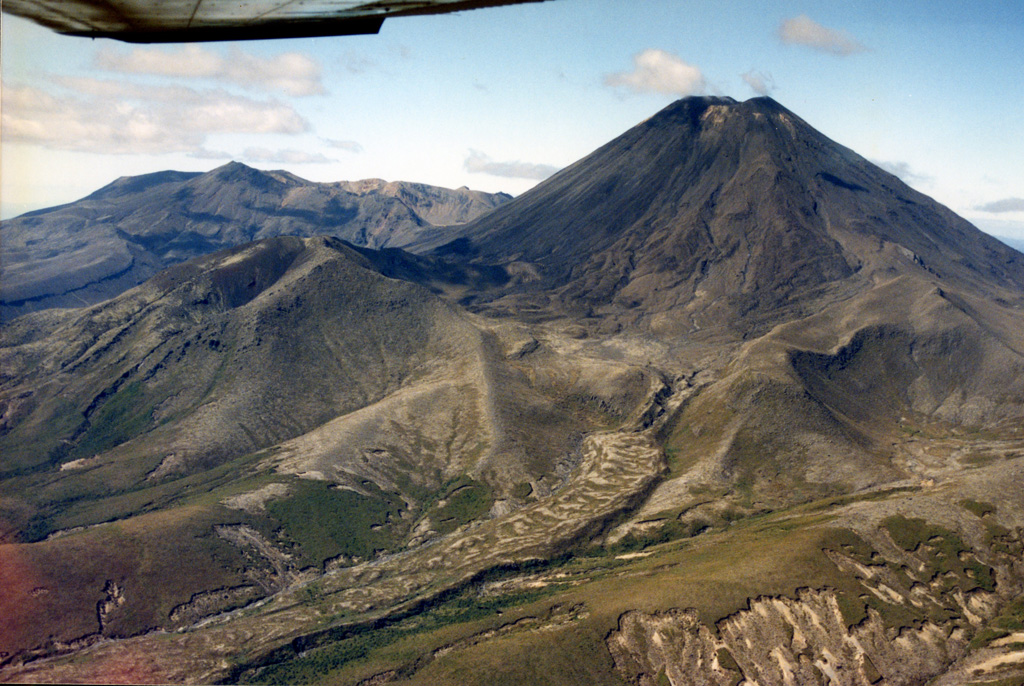 Ngāuruhoe is at the southern end of the Tongariro volcanic complex, seen here from the SW with the northern Tongariro complex to the left. Lava flows erupted during the 1954-55 eruption are visible down the flank to the left, originating from the summit scoria cone. Pukekaikiore is below the W flank (left) and is the remnant of an older eruption center of Tongariro.  Photo by John A Krippner, 1995-1996.