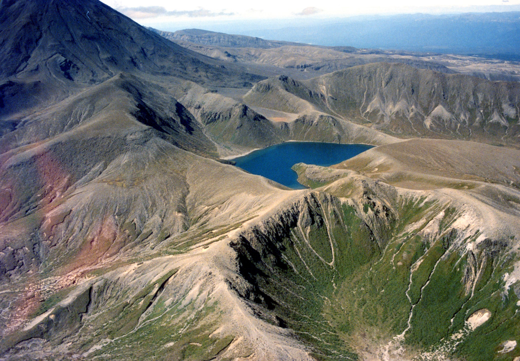 The Upper Tama Lake is in the center of this photo with the southern flank of Ngāuruhoe to the right, both of which are eruption centers of the Tongariro volcanic complex. The lake fills several craters that were active around 10,000 years ago, with lava flows s180,000-200,000 years old forming the cliffs surrounding it. Photo by John A Krippner, 1995-1996.