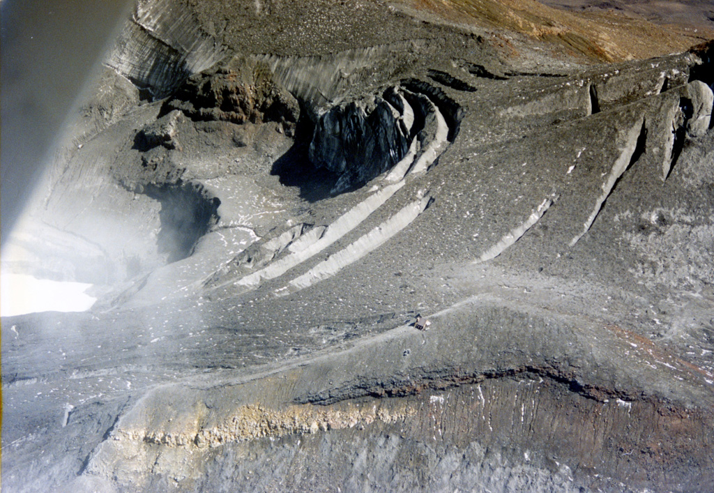 The 1995-96 eruption of Ruapehu ejected much of the water from Te Wai a-Moe (Crater Lake), with the remaining lake to the left. The lake emptied in 1995 and was reestablished in 1996. Dome Shelter is above the northern crater rim, to the left of the lake in this view, surrounded by ash and other ejecta deposited during the eruption. Photo by John A Krippner, 1995-1996.