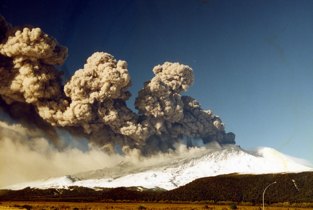 This 17 June 1996 photo shows the eruption of Ruapehu with an ash plume dispersing to the NE. The eruption varied in intensity, causing the differences in plume height with distance from the vent. Ashfall is visible across the flank and a lower plume is from the redispersal of the ash deposit. Photo by John A Krippner, 1996.