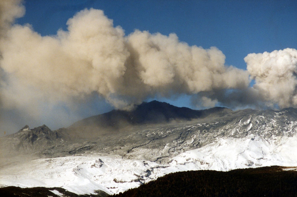 Ash was deposited across several flanks during the 1995-96 Ruapehu eruption. This weak ash plume was dispersed by the wind before it reached a significant height above the crater, with ash falling out of the plume across the dark deposit already covering the snow. Photo by John A Krippner, 1995-1996.