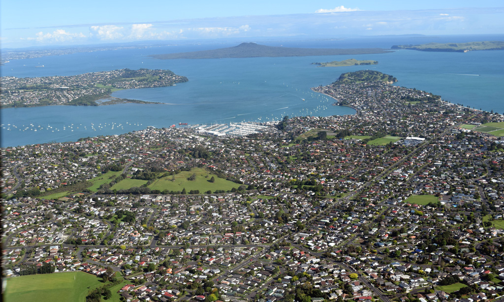 Pigeon Mountain or Ōhuiarangi is a scoria cone that has been modified by quarrying, seen in the triangular grassy area near the center of the photo. Rangitoto volcano is in the background of this 2018 photo showing part of the Auckland Volcanic Field. Photo by Bruce Hayward, 2018.