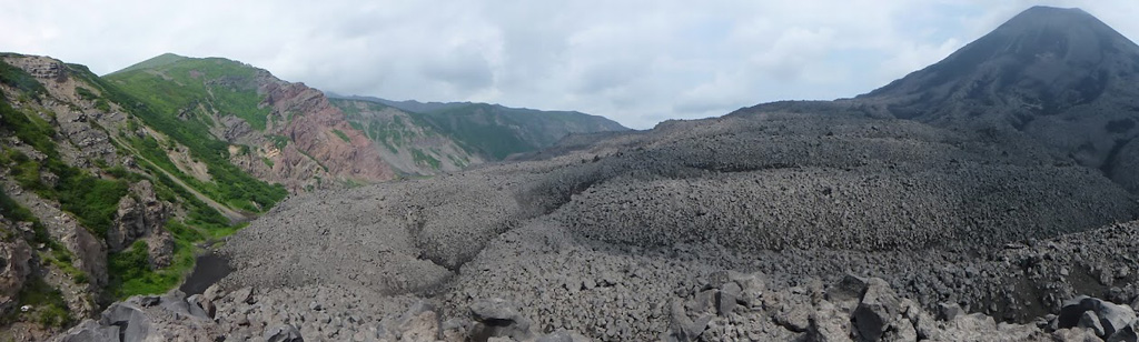 This July 2014 photo shows the lava flows across the SE lower flank of Karymsky, with the Karymsky caldera wall to the left. The caldera formed around 7,700 years ago and has been filling with lavas and other deposits from the cone since around 5,300 years ago. Lava flows within the caldera reach 80 m thick in the SE part. Photo by Janine Krippner, 2014.